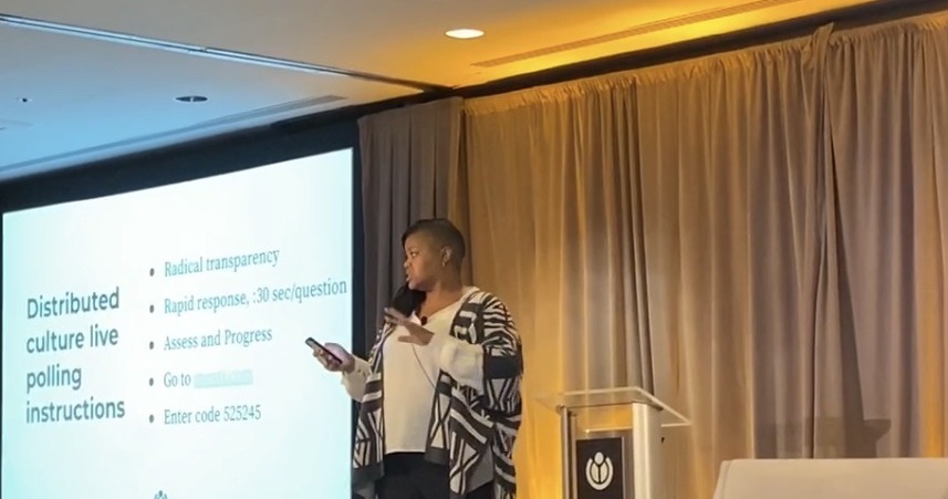 Lydia Hamilton speaking onstage while leading an interactive presentation